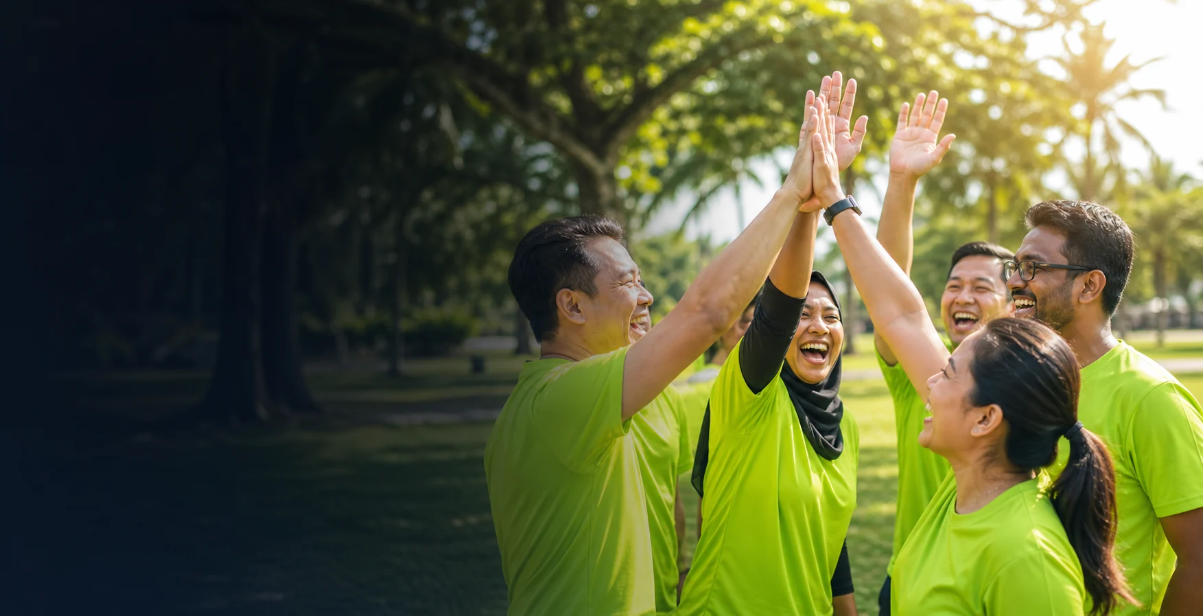 Malaysian corporate team in green shirts celebrating outdoors